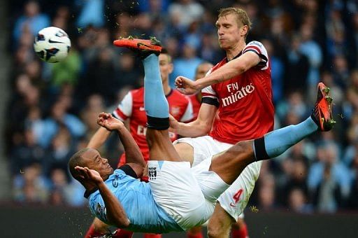 Manchester City's Vincent Kompany (L) attempts an overhead kick as Arsenal's Per Mertesacker stands clear